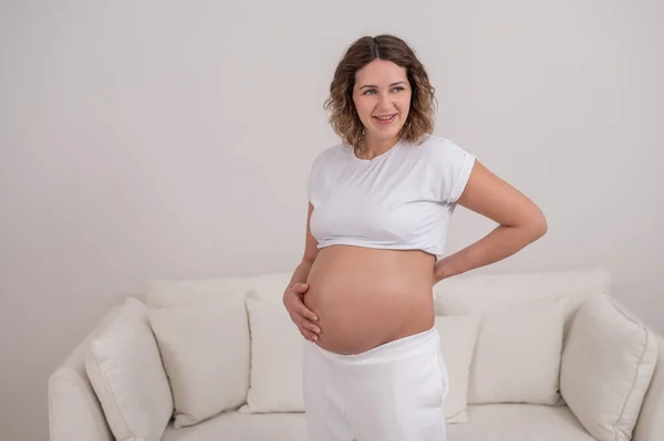 Těhotná žena drží břicho a dolní část zad. — Stock fotografie