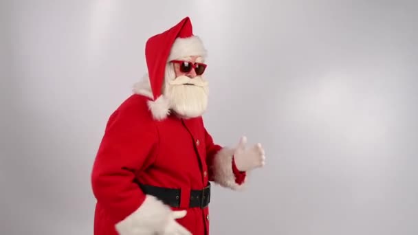 Санта Клаус у сонцезахисних окулярах біжить на білому тлі. Веселого Різдва. — стокове відео