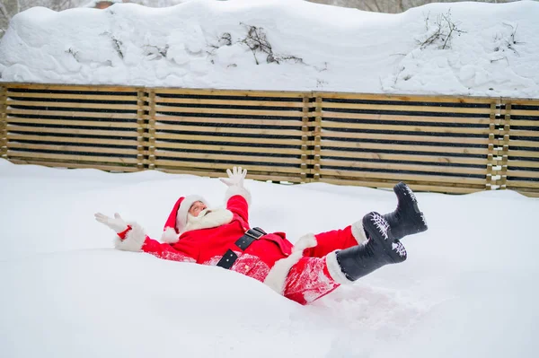 Heureux Père Noël claus couché dans la neige et de s'amuser autour — Photo