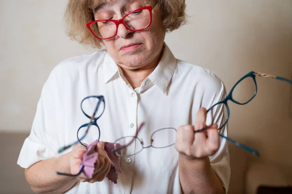 En äldre kaukasisk kvinna väljer glasögon från sin hemsamling — Stockfoto