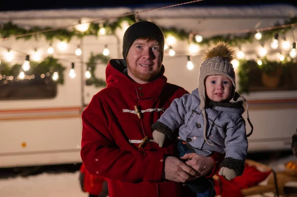 Кавказький рудий чоловік з хлопчиком на руках у пересувному будинку. Батько і син святкують Різдво під час подорожі.. — стокове фото