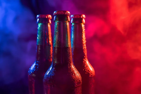 Tři láhve piva v modrorůžové mlze. — Stock fotografie