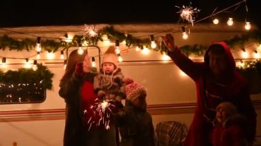 Mutlu büyük aile Noel 'i doğada kutlar ve havai fişek tutarlar. Üç çocuklu ebeveynler seyyar bir evde seyahat ediyorlar..
