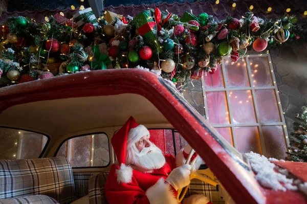 Porträtt av jultomten claus kör en bil laddad med en julgran och presenter — Stockfoto