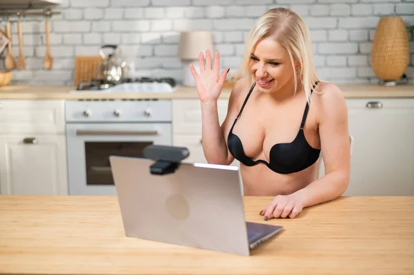 En tjej i underkläder flirtar på en webbkamera på en bärbar dator. En kvinna arbetar i online sexindustrin — Stockfoto