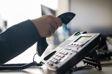 Sabit bir telefondan bir numarayı arayan kadın bir ofis çalışanının eli yakın çekim. Meçhul kadın sekreter telefonda.