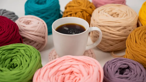 Detailní záběr mnohobarevných přadének z bavlny a hrnek černé kávy — Stock fotografie