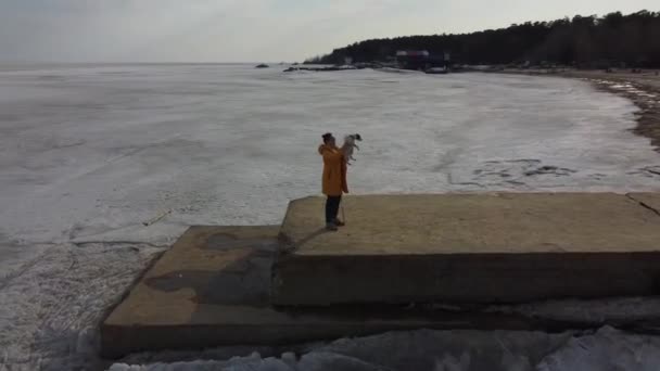 Kavkazská žena hrající si se psem Jackem Russellem teriérem na molu zamrzlé nádrže — Stock video