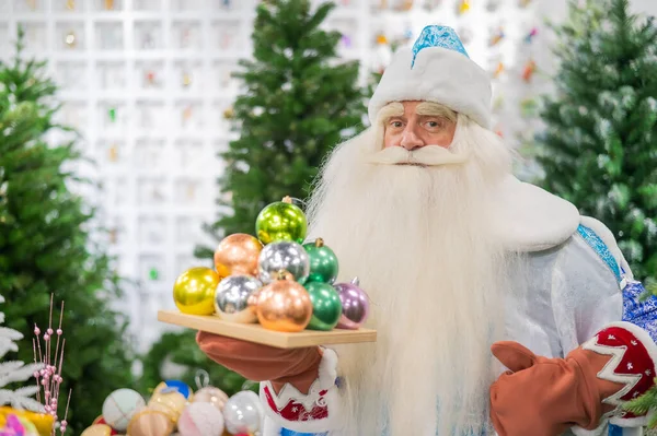 Russian santa claus holds decorations for the christmas tree in the store. — Stock Photo, Image