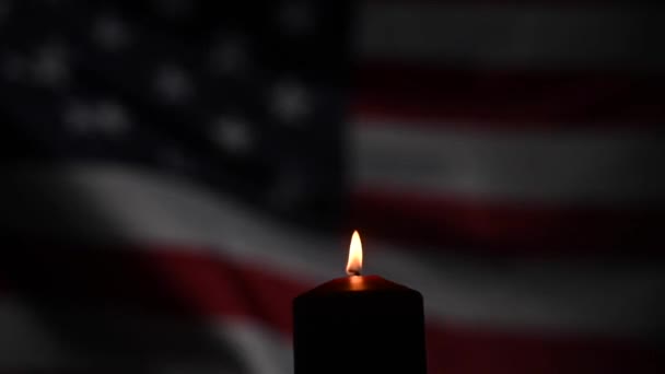 Égő gyertya az Amerikai Egyesült Államok lobogtató zászlajának hátterében a sötétben. — Stock videók