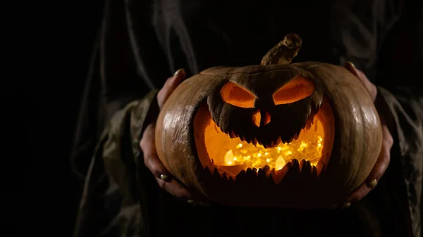 A boszorkány egy tök Jack O lámpást tart, ami világít a sötétben. Halloweeni. — Stock Fotó