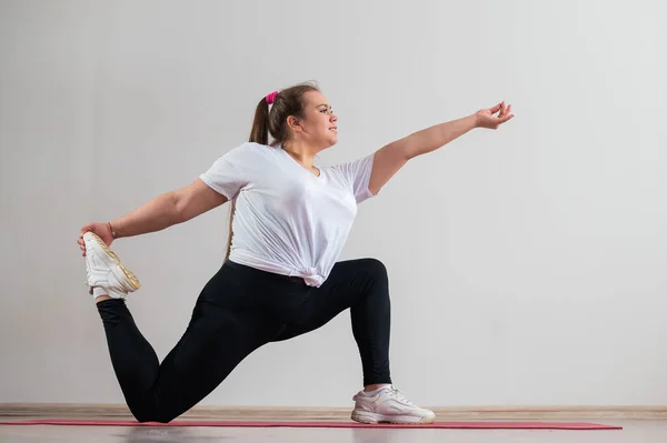 Jeune femme grosse faisant des exercices de flexibilité sur un fond blanc — Photo