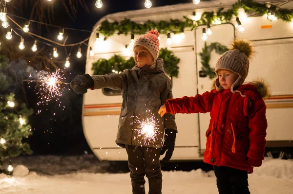 Kaukasiska rödhåriga pojkar håller tomtebloss vid husvagnen. Två bröder firar jul på en resa. — Stockfoto