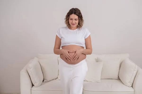 妊娠中の女性は胃の上に心臓の形で手を握っています. — ストック写真