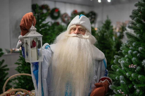 Russian Santa Claus is holding a candlestick in a Christmas tree shop. — Stock Photo, Image
