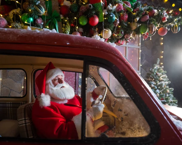Портрет Санта-Клауса за рулем автомобиля, загруженного елкой и подарками — стоковое фото