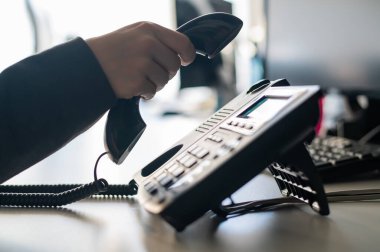 Sabit bir telefondan bir numarayı arayan kadın bir ofis çalışanının eli yakın çekim. Meçhul kadın sekreter telefonda.