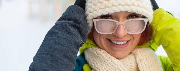 Blanke vrouw met glazen glimlachen en bevriezen buiten in de winter. — Stockfoto