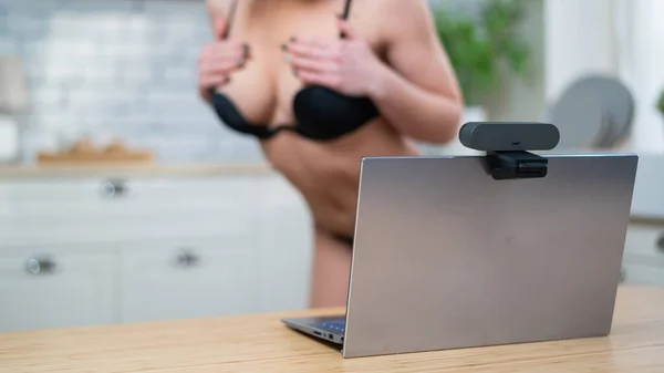 Девушка в нижнем белье флиртует с веб-камерой на ноутбуке. Женщина работает в секс-индустрии онлайн — стоковое фото