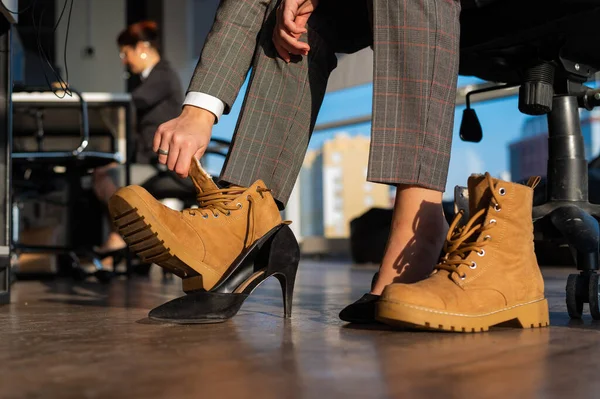 사업을 하는 여성은 사무실에서 부츠에 하이힐을 신고 신발을 갈아 신는다. 근무 시간의 끝. 피곤 한 다리 — 스톡 사진