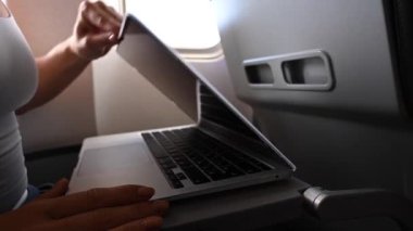 Maskeli meçhul kadın uçuş sırasında pencerenin yanında otururken dizüstü bilgisayarda çalışıyor. Serbest Çalışan Bir Yolculuk.