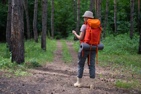 Mujer joven caucásica está haciendo senderismo y utilizando una brújula en el bosque. — Foto de Stock