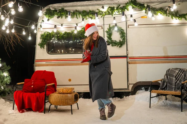 Vit kvinna i tomte hatt spelar snöbollar på husbil. — Stockfoto