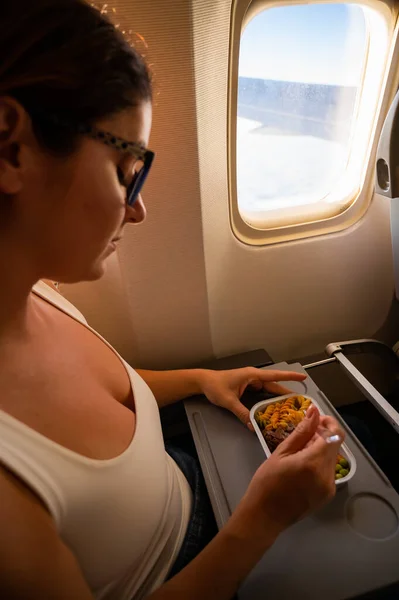 Mujer caucásica volando en clase económica y almorzando en una bandeja a bordo del avión. — Foto de Stock