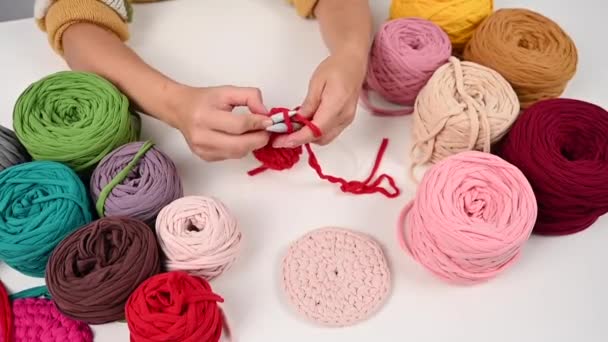 Top view of female hands with knitting on a white table. A woman knits a basket of red cotton yarn. — Stock Video