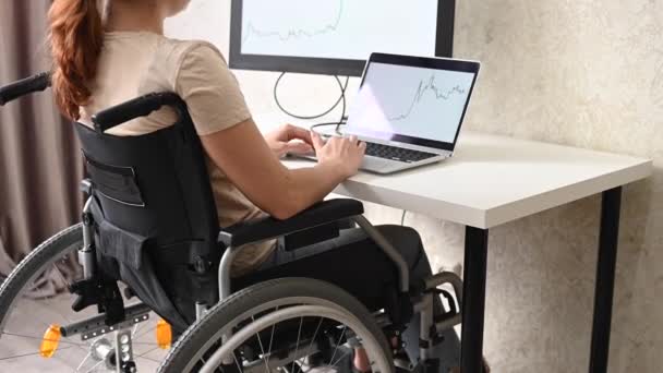 Blanke vrouw met een handicap werken aan de computer tijdens het zitten in een rolstoel ziekte. — Stockvideo