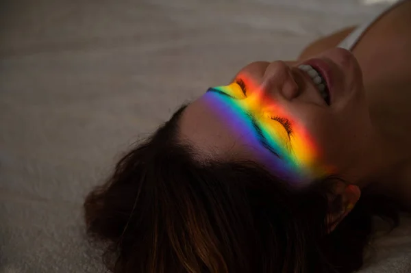 Retrato de cerca de una mujer sonriente con rayo de luz del arco iris en su cara. —  Fotos de Stock