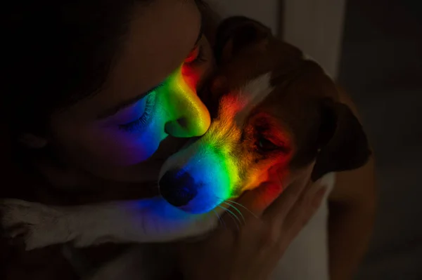 Close-up retrato de uma mulher abraçando um cão terrier jack russell com um raio de luz do arco-íris em seu rosto. — Fotografia de Stock