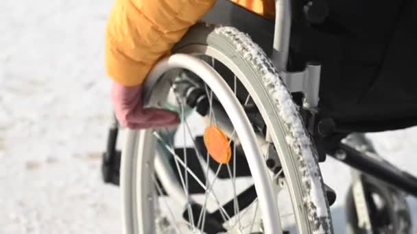 Gros plan des mains d'une femme handicapée en fauteuil roulant à l'extérieur en hiver. — Video