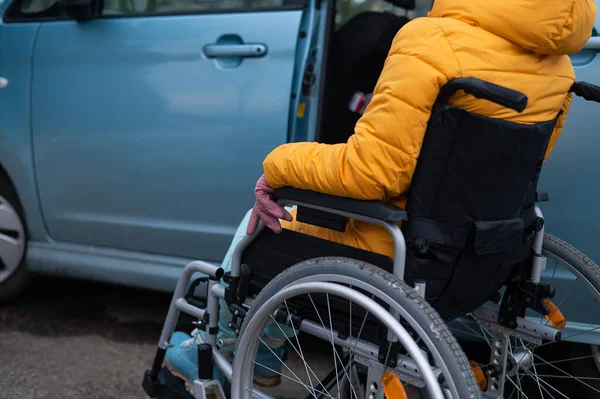 Белая женщина в инвалидном кресле садится в машину. — стоковое фото