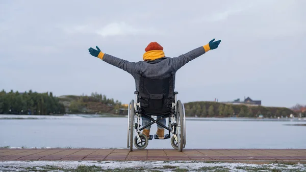 Blanke vrouw in een rolstoel wandelingen door het meer in de winter. — Stockfoto