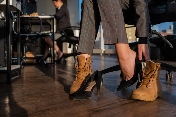 Femme d'affaires change de chaussures avec des talons hauts sur les bottes dans le bureau. Fin de journée de travail. Jambes fatiguées — Photo