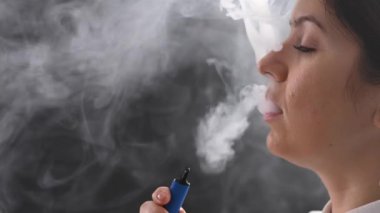 Beyaz kadın stüdyoda tek kullanımlık bir sigara içiyor..