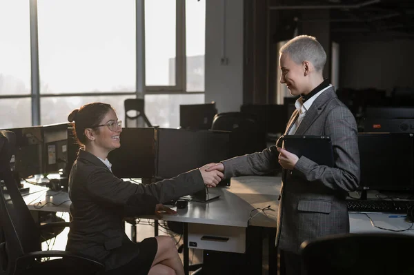 Zwei junge Geschäftsfrauen geben sich bei der Arbeit die Hand. Die Büroangestellten machten einen Deal — Stockfoto