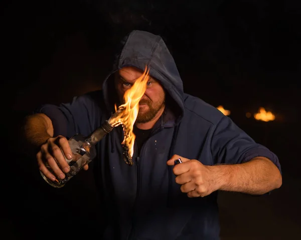 Kapüşonlu adam yanan bir şişe tutuyor. Molotof kokteyli. — Stok fotoğraf