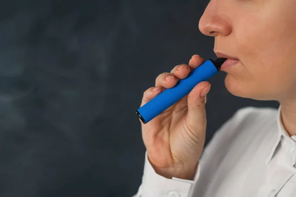 Mujer caucásica fuma un vapor desechable en el estudio. — Foto de Stock