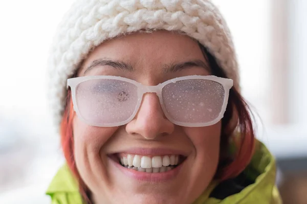 Porträtt av en rödhårig vit kvinna i vit stickad mössa och iskalla glasögon utomhus i frosten — Stockfoto