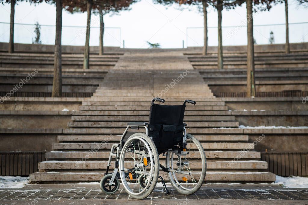Wheelchair by the stairs without people outdoors. 