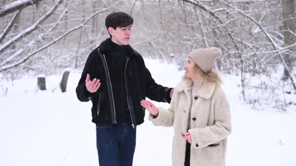 若い夫婦が森の中で冬を歩いている。ろう者男と女の子は屋外でジェスチャーを使用して通信します. — ストック動画