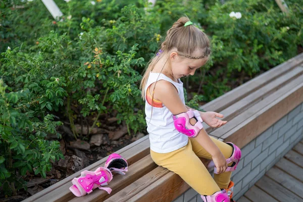 Little caucasian girl puts on protection before roller skating. — Foto Stock