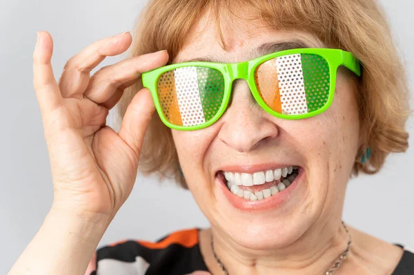 Porträtt av leende äldre kvinna bär glasögon med Irlands flagga. — Stockfoto