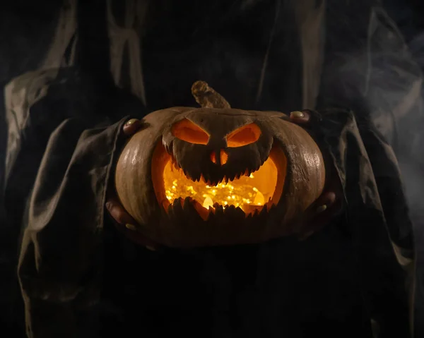 La bruja sostiene un gato de calabaza o linterna que brilla en la oscuridad. Halloween. —  Fotos de Stock