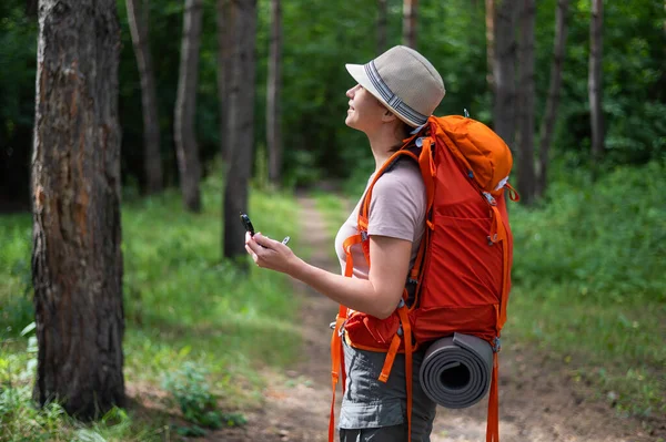 Jeune femme caucasienne fait de la randonnée et utilise une boussole dans la forêt. — Photo