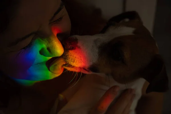 Close-up retrato de uma mulher abraçando um cão terrier jack russell com um raio de luz do arco-íris em seu rosto. — Fotografia de Stock