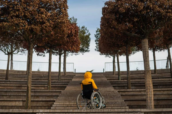 Mujer en silla de ruedas delante de las escaleras en la calle en invierno. — Foto de Stock