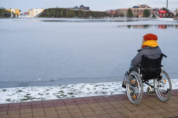 Donna caucasica in sedia a rotelle passeggiate al lago in inverno. — Foto Stock